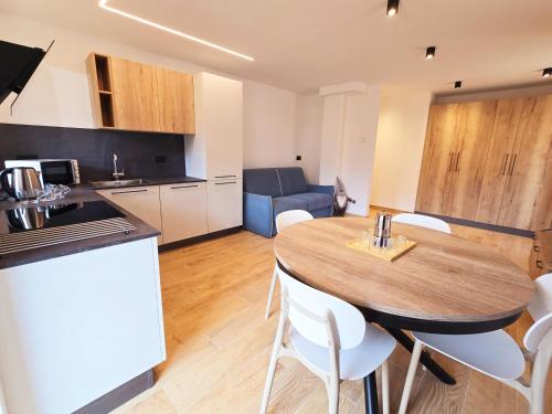 una cucina e una sala da pranzo con tavolo e sedie di Alpine Lodge Tesero - Alpine Stay Apartments a Tesero
