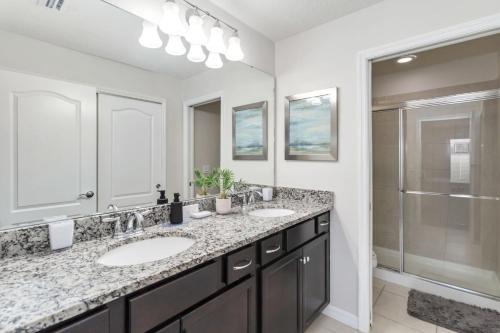 un baño con dos lavabos y una ducha en 5BR Poolside Retreat, en Kissimmee