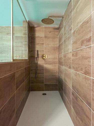 La salle de bains est pourvue d'une douche avec du carrelage brun. dans l'établissement Villa l'Esneval & Spa - Normandie, à proximité d'Etretat, à Criquetot-lʼEsneval