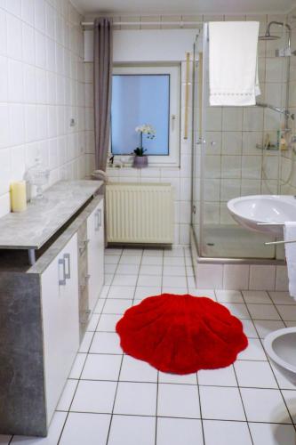a white bathroom with a red rug on the floor at Ferienwohnung Pasch-Wittke in Geldern