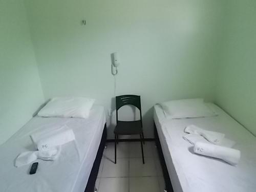 two twin beds in a room with a chair at Pousada Cariri in Juazeiro do Norte