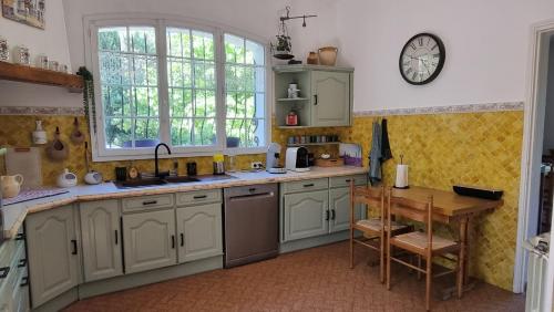 une cuisine avec une table et une horloge au mur dans l'établissement Magnifique villa avec piscine, à La Bouilladisse