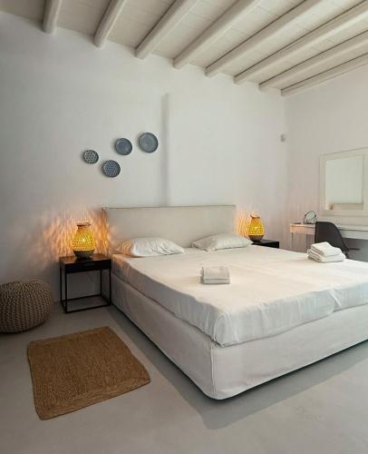 a white bedroom with a large bed and two lamps at VILLA AGNES MYKONOS in Mikonos