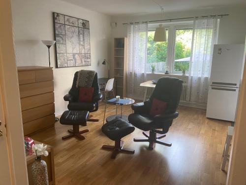 a living room with chairs and a table and a refrigerator at Fingal 9 studio apartments in Landskrona
