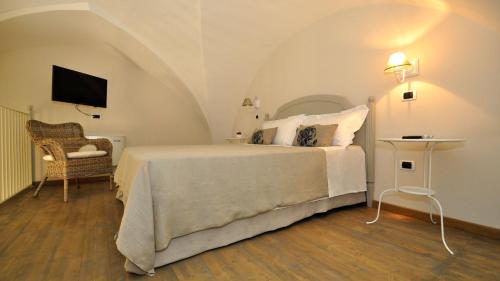 a bedroom with a white bed and a chair at Don Alfonso Dimora D'epoca in Racale