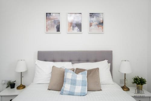a bedroom with a white bed with pillows and two lamps at Modern 3 bedroom - Olympic Park - E20 Stratford in London