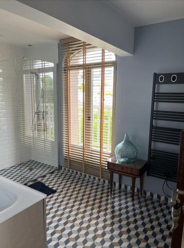 une salle de bain avec une baignoire et une table avec un vase dans l'établissement Villa Médaillon, Sur la mer - Mesnil Val Plage, à Criel-sur-Mer