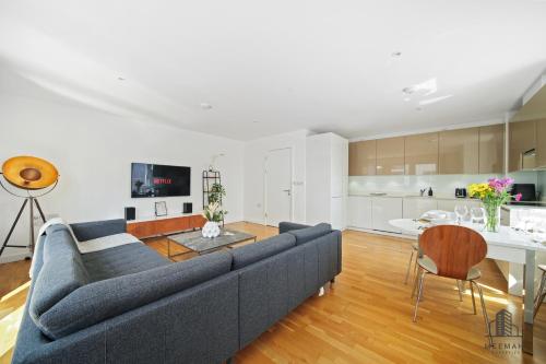 a living room with a blue couch and a kitchen at Modern 3 bedroom - Olympic Park - E20 Stratford in London