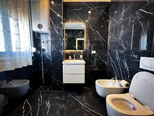 a black bathroom with a sink and a toilet at Rooftop Florale in Velipojë