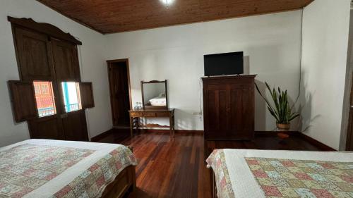 a bedroom with two beds and a flat screen tv at El Balcón de Emma in Jardin