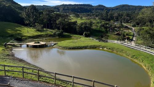 a river with a bridge in the middle of a field at Rota do Engawno in Barracão