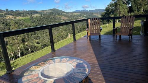a wooden deck with two chairs and a glass table at Rota do Engawno in Barracão