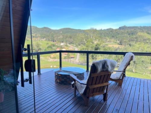 a wooden deck with a chair and a table and a view at Rota do Engawno in Barracão