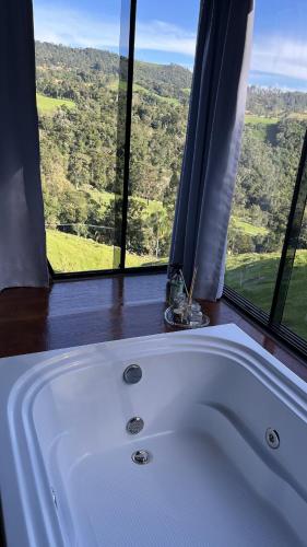 a white bath tub in a room with a window at Rota do Engawno in Barracão