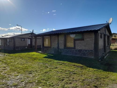 a house with a grass yard in front of it at CABAÑAS TREVELIn in Trevelin