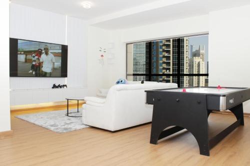 a living room with a white couch and a pool table at Emirat Premium DxB in Sabkhah