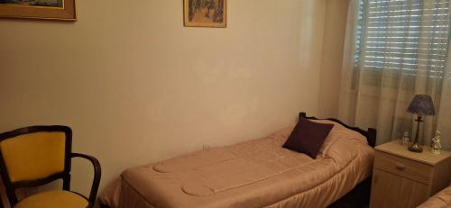 a small bed in a room with a chair and a window at Dos habitaciónes independientes con baño privado en casa familiar in Vicente López