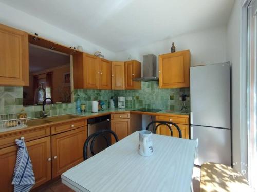 Il comprend une cuisine équipée d'une table blanche et d'un réfrigérateur. dans l'établissement Large family villa, à Marseillan