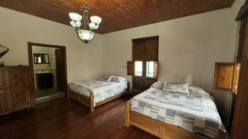 a bedroom with two beds and a chandelier at El Balcón de Emma in Jardin