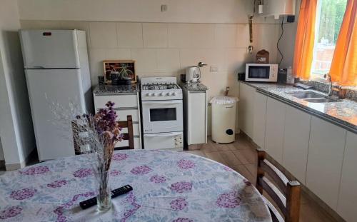 Una cocina con una mesa y un refrigerador blanco. en EnSueños Tandil, en Tandil