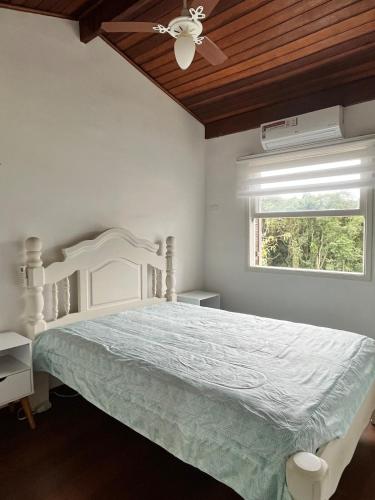 a bedroom with a bed with a ceiling fan and a window at Apartamento Duplex em Juquehy in São Sebastião