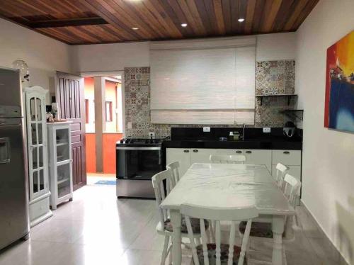a kitchen with a table and a white table and chairs at Apartamento Duplex em Juquehy in São Sebastião