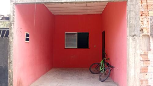 a bike parked against a red wall with a window at moradia in Ananindeua