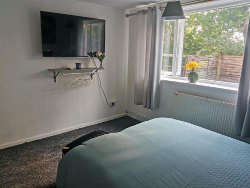a bedroom with a bed and a television and a window at Brendon Rooms Luton Airport in Luton