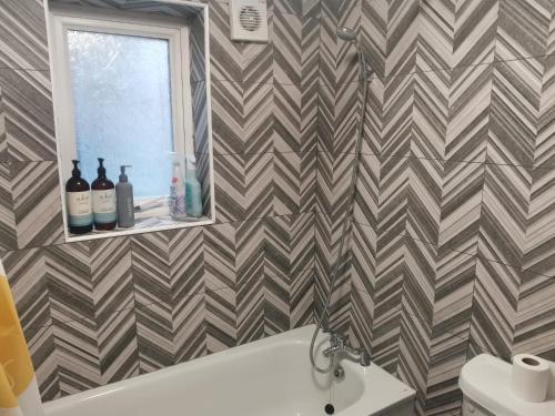 a bathroom with a chevron wallpaper with a tub and a window at Brendon Rooms Luton Airport in Luton