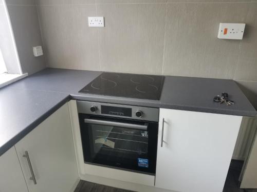 a kitchen with a stove and white cabinets at Brendon Rooms Luton Airport in Luton