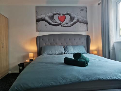 a woman laying on a bed with two hands holding a heart at Brendon Rooms Luton Airport in Luton