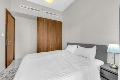 a bedroom with a white bed and a wooden door at Wonderful Reva Aparthotel Downtown in Dubai