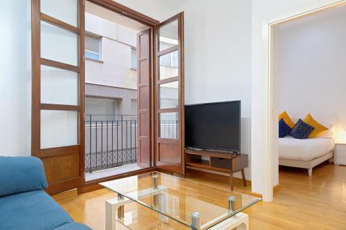 a living room with a blue couch and a tv at Grand Central Market Suites By VALENCIAFLATS EU in Valencia