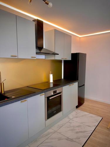  La cuisine est équipée de placards blancs et d'un réfrigérateur. dans l'établissement Superbe appartement moderne en bord de Seine - proche Paris, à Villeneuve-la-Garenne
