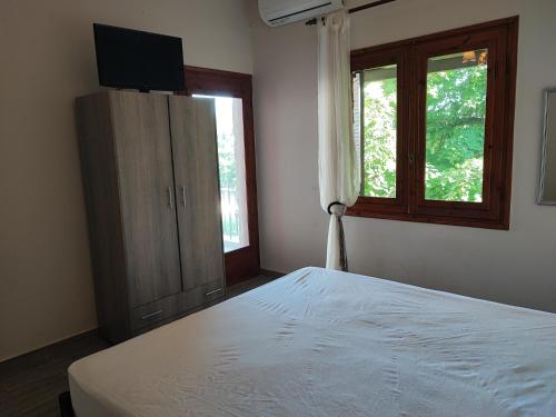 a bedroom with a bed and a dresser with a television at Stone house with seaview in Nea Potidaea