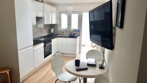 a kitchen with a table and chairs and a television at Bright 1 bedroom guest house in Norwood