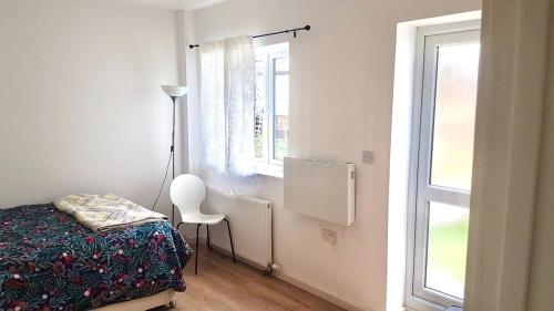 a bedroom with a bed and a chair and a window at Bright 1 bedroom guest house in Norwood