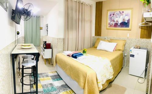 una piccola camera da letto con un letto e un tavolo di Studio em vila a 100m praia do recreio a Rio de Janeiro