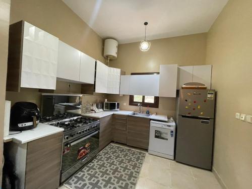 a kitchen with white cabinets and a stainless steel refrigerator at Amazing 3br Villa in Emaar - Mivida in New cairo