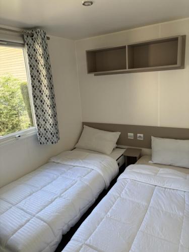 deux lits assis dans une pièce avec une fenêtre dans l'établissement Location de Mobil-home 6 à 8 personnes , Vias Camping la Carabasse, à Vias