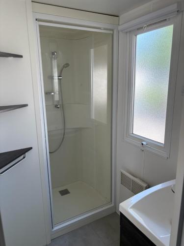 une salle de bain avec une douche avec une porte vitrée dans l'établissement Location de Mobil-home 6 à 8 personnes , Vias Camping la Carabasse, à Vias