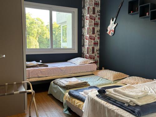 Dos camas en una habitación con una guitarra colgada en la pared. en Altos da Bela Vista, en Gramado