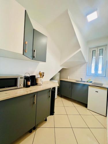 La cuisine est équipée de placards verts et d'un four micro-ondes. dans l'établissement Grand studio dans villa - Emplacement unique - Proche mer - Clim - Grande Terrasse, à Nice