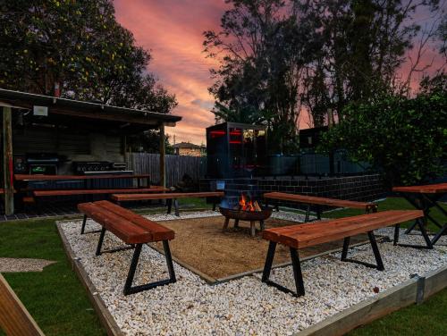 a group of picnic tables and a fire pit at Skyes Beach House-Views, Spas, Sauna, Arcade Games in Surf Beach