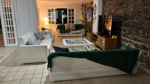 a living room with white furniture and a stone wall at GUEST HOUSE Floresta Mar in Angra dos Reis