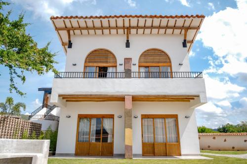 a white house with wooden doors and a balcony at Hotel campanario campestre barichara in Barichara