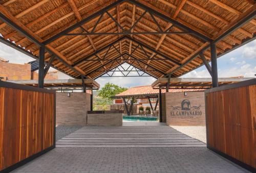 a wooden pavilion with a pool in the background at Hotel campanario campestre barichara in Barichara