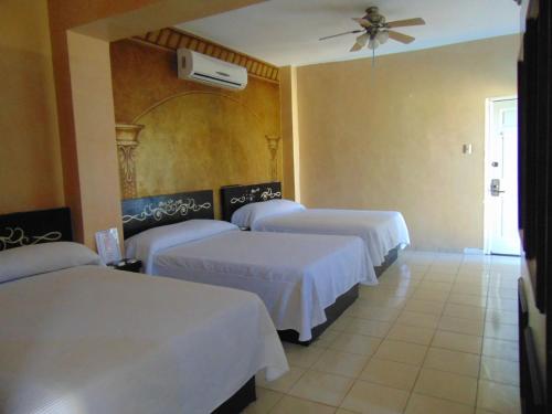 a hotel room with three beds and a ceiling fan at Hotel Jardin in Heroica Caborca