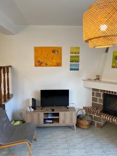 a living room with a television and a fireplace at Seashell Consolação in Atouguia da Baleia