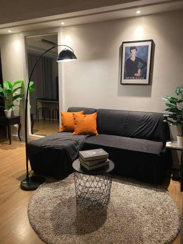 a living room with a black couch and a table at 1 Bedroom with Balcony in Abreeza Mall in Davao City